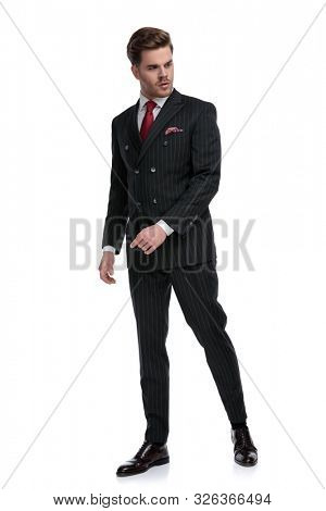 fashion businessman wearing double breasted suit and elegant brogue shoes, looking to side, walking isolated on white background