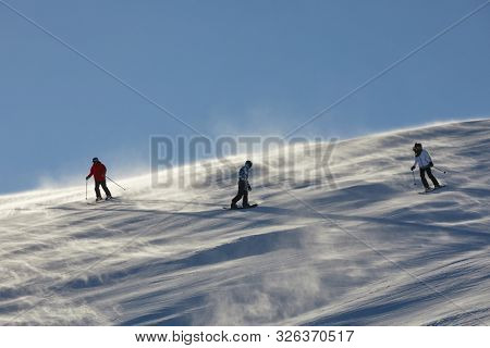 BRIANCON, FRANCE - JANUARY 22, 2019: Skiers sliding down a snowy slope with strong winds blowing the snow around