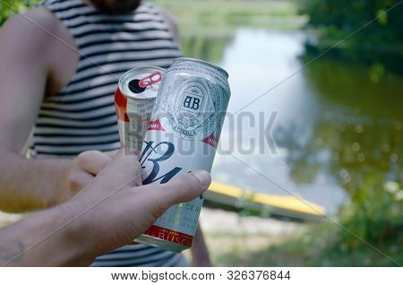 Sumy, Ukraine - August 10, 2019: Young Man Raise Budweiser Bud Beer Can With Male Friend On Blurred 