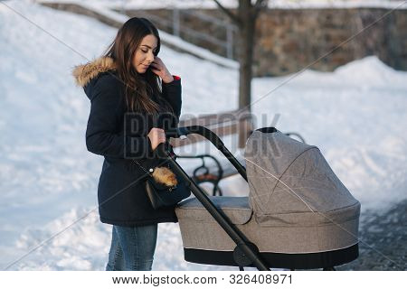 Young Mother Walking With Her Baby In Pram. Beautiful Stoller. Winter Photosession