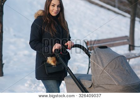 Young Mother Walking With Her Baby In Pram. Beautiful Stoller. Winter Photosession