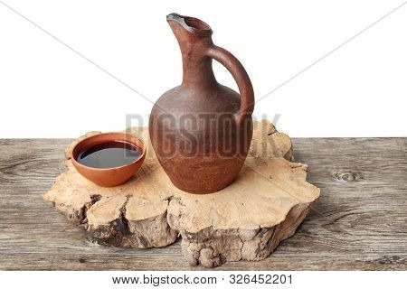A Traditional Georgian Wine Jug And Clay Cup Filled With A Red Wine On The Wooden Table, Isolated Ba