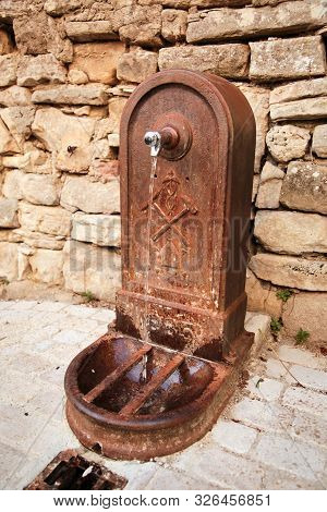 Old Metal Street Water Tap Near The Sandstone Wall. Element Of Urban Improvement In Barjac, France
