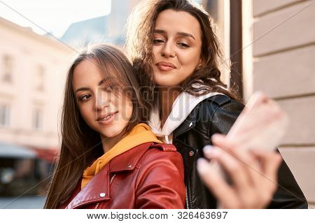 Two Beautiful Funny Young Women Making Selfie By The Phone Uotdoors In City