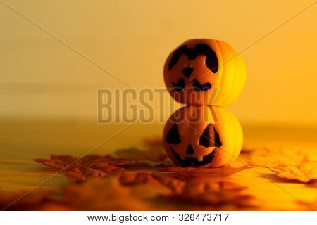 Halloween Pumpkins With Painted Faces On A Wooden Table. Halloween Background. Space For Text. Copy
