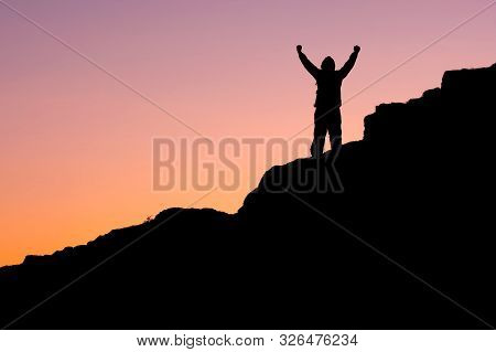 On The Mountain, The Silhouette Of A Man With His Hands Up Against The Dark Sky. Overcame A Steep Cl