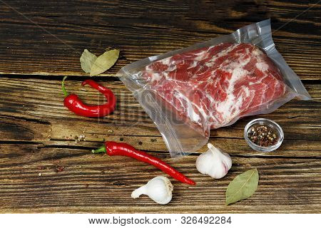 Meat In A Vacuum Bag On A Wooden Background.