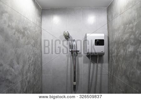 Instant Tankless Electric Water Heater Installed On Grey Tile Wall With Input And Output Pipe Outlet
