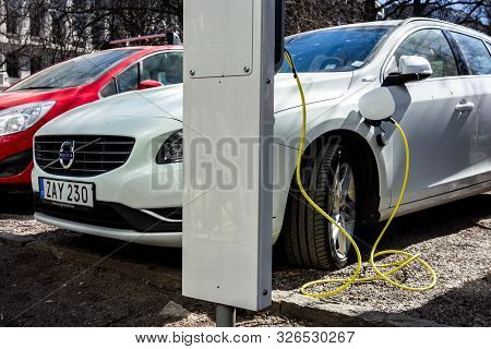 Stockholm, Sweden - April 18, 2019: White Modern Plug-in Volvo V60 Car Plugged And Charging Its Batt