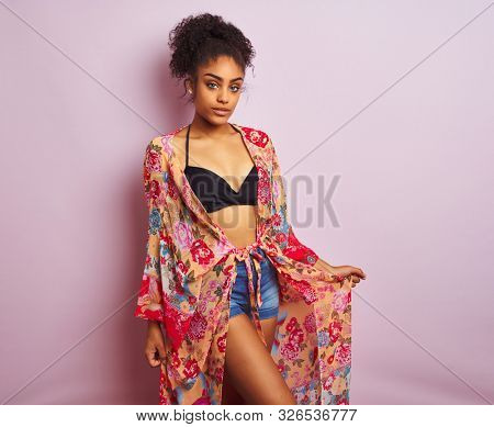 Young beautiful african american woman on vacation standing wearing bikini and colorful caftan
