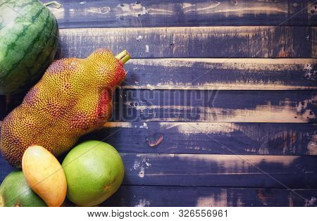 An Assorted Tropical Fruits (watermelon, Jackfruit, Pomelo, Grapefruit, Mango) Resting On A Black Di