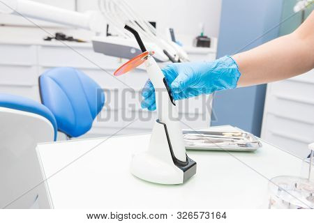 A Doctors Hand Holding A Polymerization Uv Lamp. Polymerization Lamp.