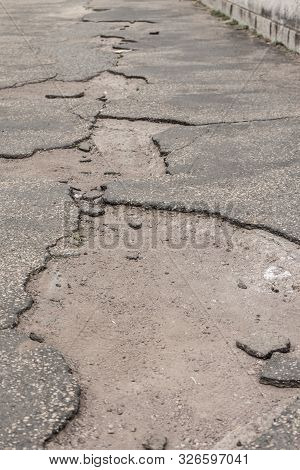Ailing Pothole Road Requires Important Infrastructure Investment. Neglected Street With Potholes Dam