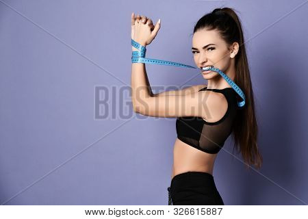 Determined Sporty Woman In Sportswear Shorts And Bralet With Her Hands Tied With A Measure Tape Is T