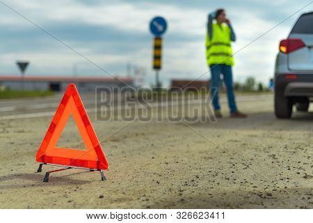 Vehicle Breakdown And Warning Triangle On The Road, Woman Using Phone To Ask For Help And Roadside A