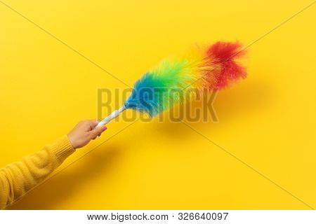 Colorful Feather Duster In Hand On Yellow Background. Cleaning Concept.