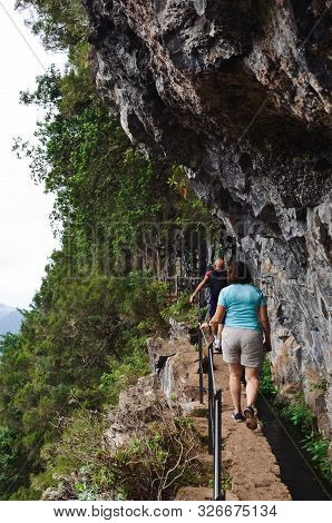 People Walking On A Narrow Path On The Edge Of The Rock During Levada Do Caldeirao Verde Trail. Rock