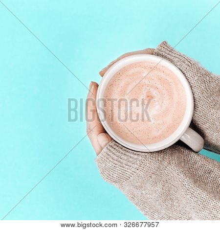 Women's Hands With Cup Of Coffee Above Trend Color Blue Paper Surface. Sweet Hot Fragrant Cappuccino