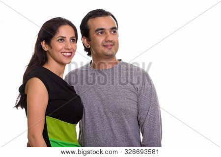 Studio Shot Of Happy Persian Couple Smiling And Looking At Dista