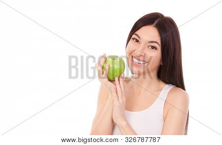 Cute woman with beautiful snow-white smile holding green apple. Healthy lifestyle and nutrition, dieting, weight loss, cosmetology, dental care and healthy teeth con?ept. Close up portrait