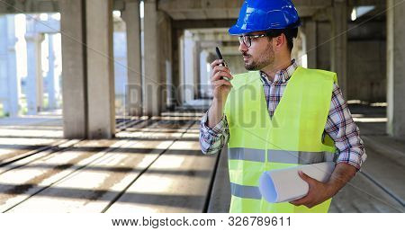 Male Architect Communicating On Walkie-talkie At Site