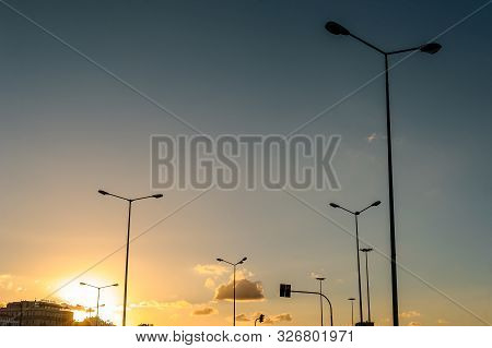 The Road For Cars At The Sunset With Big Amount Of Lanterns And A Traffic Light. Blue Sky Before The