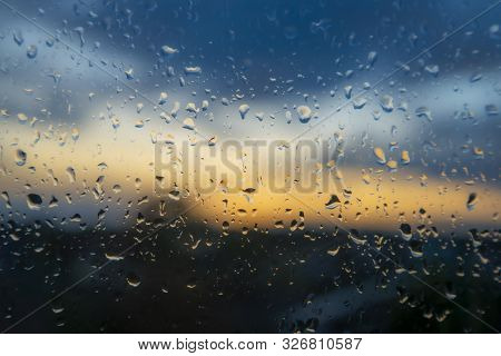 Colorful Sunset Through Wet Window Glass With Beaded Raindrops And Rivulets Of Water On A Stormy Day