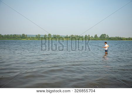 A Fisherman Catches Fish Standing In The Water Of River Tom In Kemerovo, Siberia, Russia