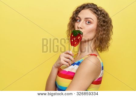 View From Side Of Pretty Woman Looking At Camera And Smiling While Keeping Ice Cream In Hands On Yel