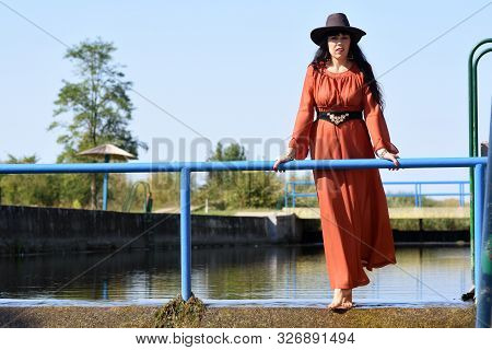 Women On Red Dress With Hat Staying In Wather