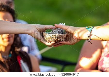 A Close Up View On The Hands Of Two Spiritual People, Passing Sacred Objects During An Outdoor Meeti