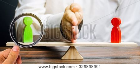 Wooden Figures Of People On Scales And A Mediator / Arbitrator. Resolving Conflict Situations And Di