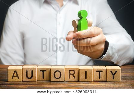 A Man Holds Figures Of People In A Fist And The Word Authority. High Status And Respect, Reputation 