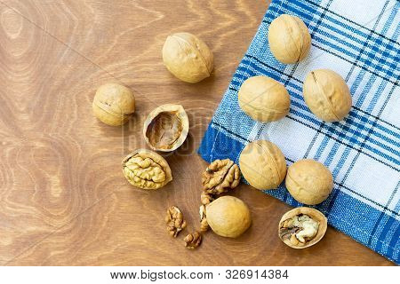 Whole Walnuts And Walnut Kernel Halves Without Shell On A Dark Wooden Table And Checkered Towel, Clo