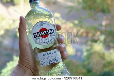 Kharkov, Ukraine - September 23, 2019: Bottle Of Vermouth Martini Rossi In Male Hand On A Green Tree