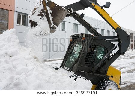 A Small Snowplow Tractor Removes Snow Drift From The Street. Selective Focus.