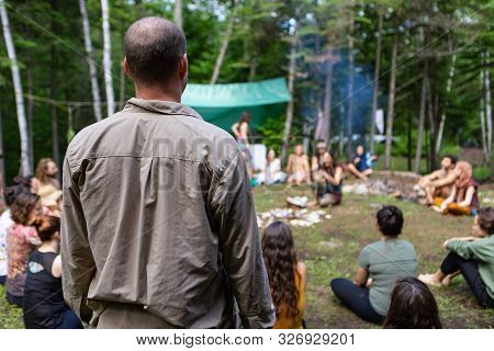 A Middle Aged Guy With A Bald Spot Is Viewed From Behind, Standing Amongst A Group Of Intergeneratio