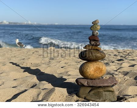 Pebbles Stacked On Malibu Beach At Pacific Ocean