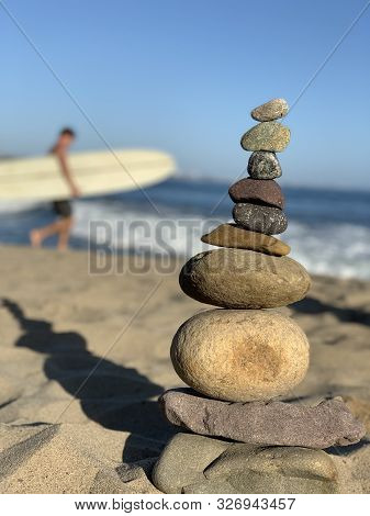 Pebbles Stacked On Malibu Beach At Pacific Ocean Surfer