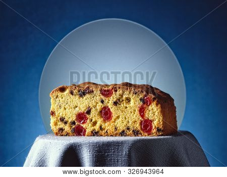 A Slice Of Fruit Cake With A Frosted Glass And A Blue Background Lies On A Grey Table Cloth