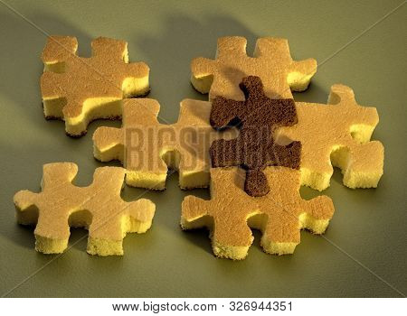 Vanilla And Chocolate Sponge Cakes Cut In The Shape Of Puzzle Pieces On A Green Paper Background