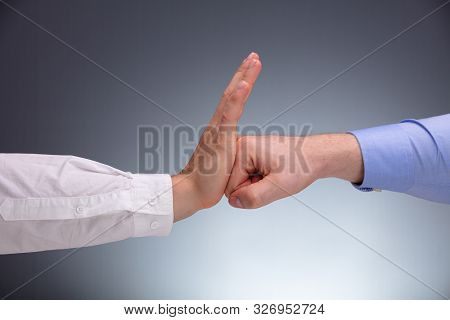 Close-up Of A Businessman Defending Himself From Punch Against Gray Background