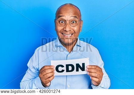 Middle age latin man holding cdn message paper celebrating crazy and amazed for success with open eyes screaming excited. 