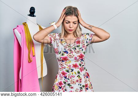 Beautiful caucasian woman dressmaker designer by manikin suffering from headache desperate and stressed because pain and migraine. hands on head. 