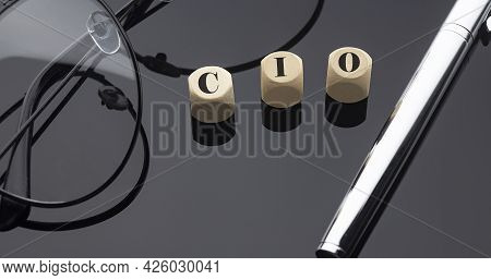 Cio Concept, Words On Wooden Blocks On Black Background With Pen And Glasses.