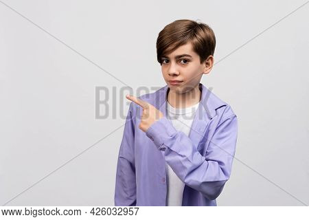 Handsome Boy 12-14 Years Old Looking At The Camera And Showing Aside On Copyspace. Pay Attention To 