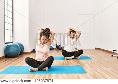 Mature hispanic couple doing excersice and stretching at yoga room. Two adult people doing pilates and flexibility workout