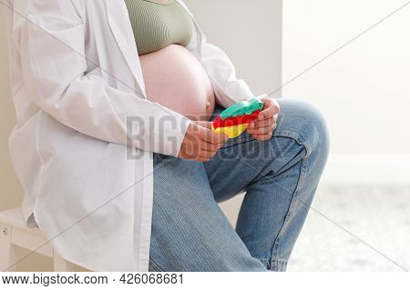 Pregnant Woman With Big Belly Advanced Pregnancy Is Using Anti Stress Toy Poppit And Sitting On Chai