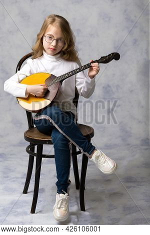 Cute Little Girl Learning To Play The Plucked Musical Instrument, Domra.