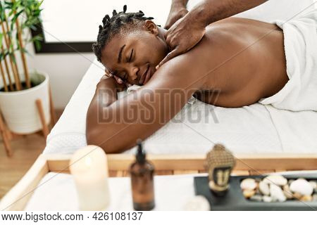 African american woman reciving back massage at the clinic.